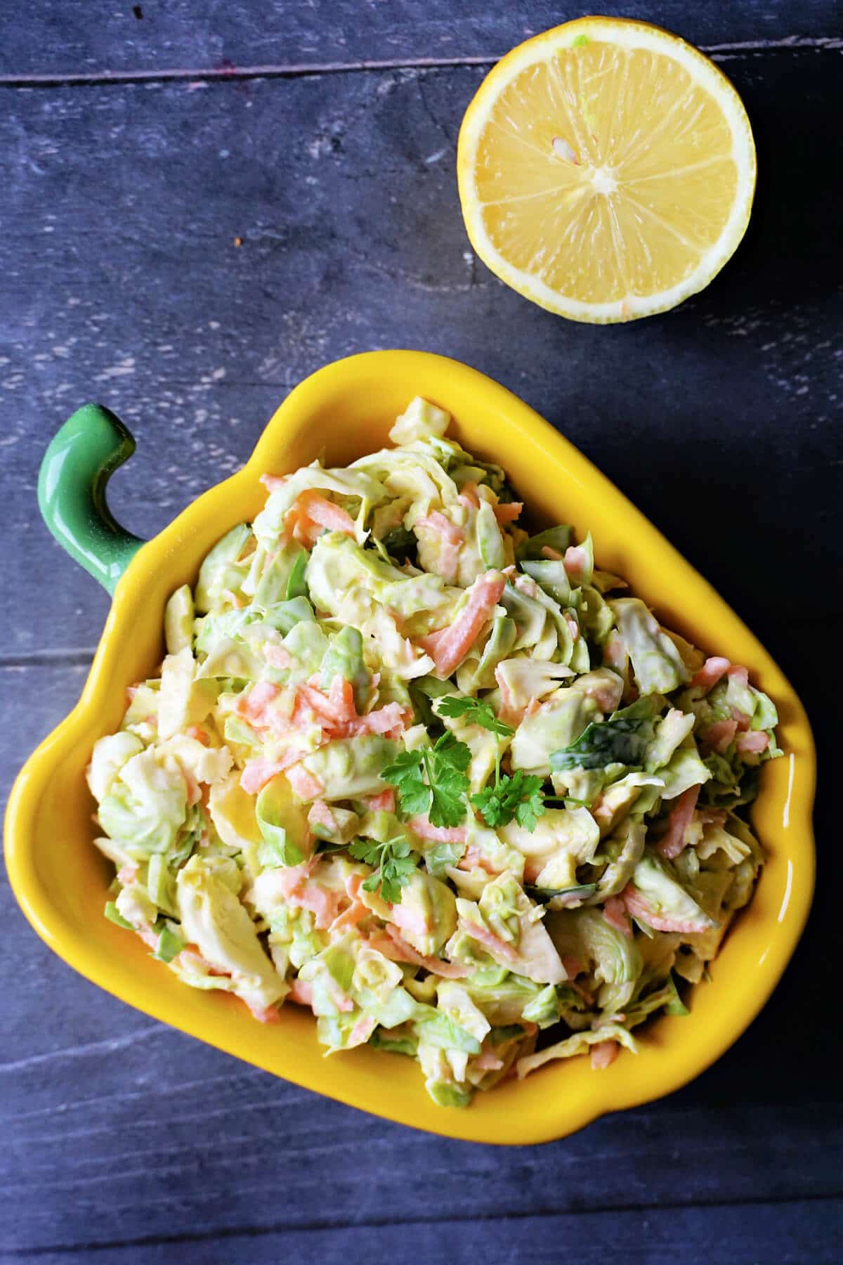 Overhead shoot of a yellow peppered-shaped dish with brussel sprout slaw.