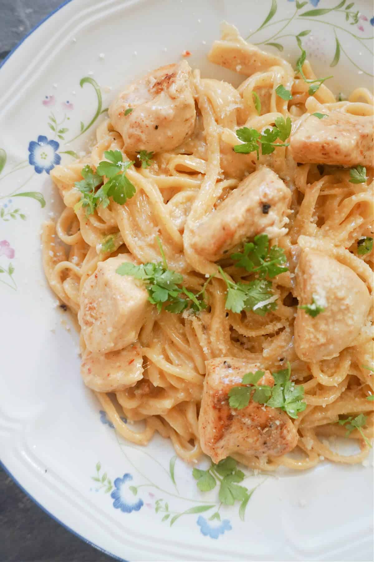 A white plate with spaghetti in creamy cajun chicken sauce.