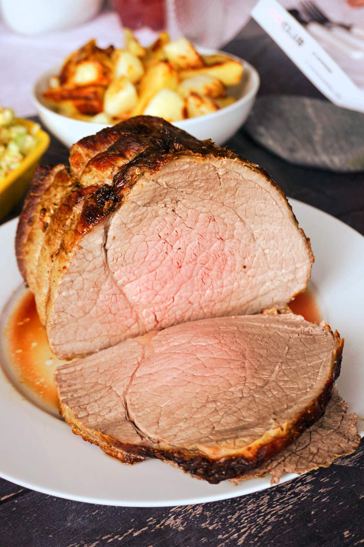 A roast beef sliced with a slice on a white plate.