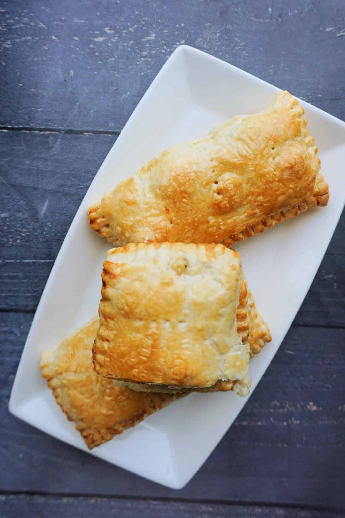 Overhead shoot of a white rectangle plate with 2 whole chicken pasties and a half pasty.