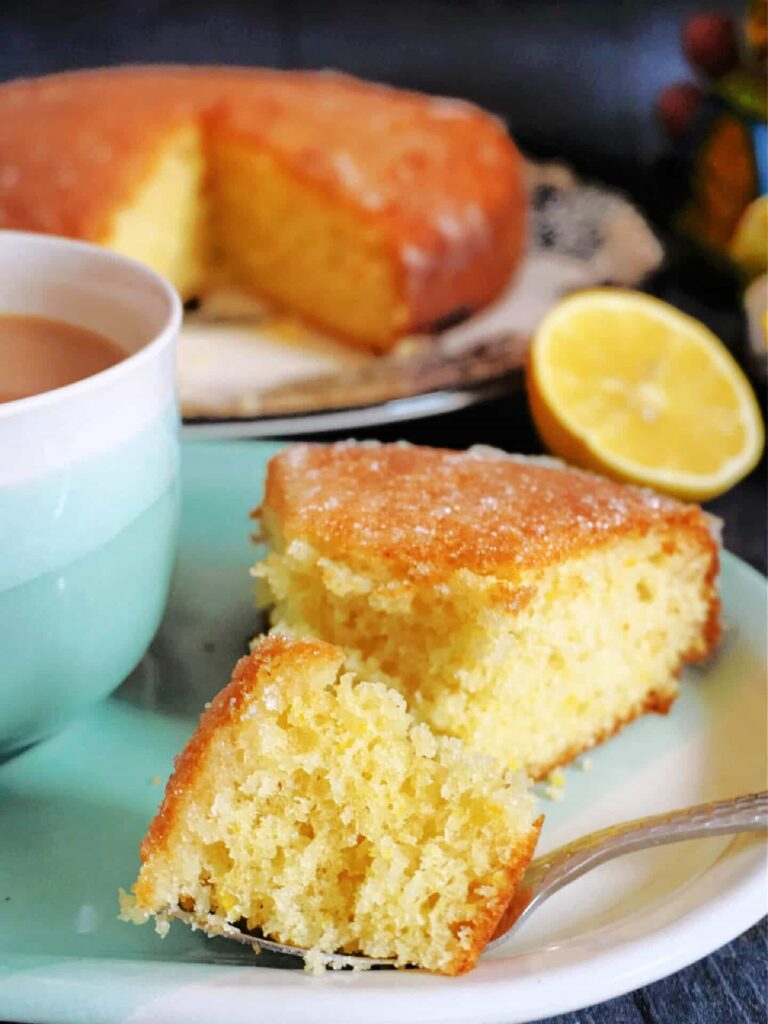 A slice of lemon drizzle cake being cut on a plate