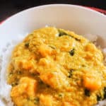 A white plate with rice and red lentil dhal