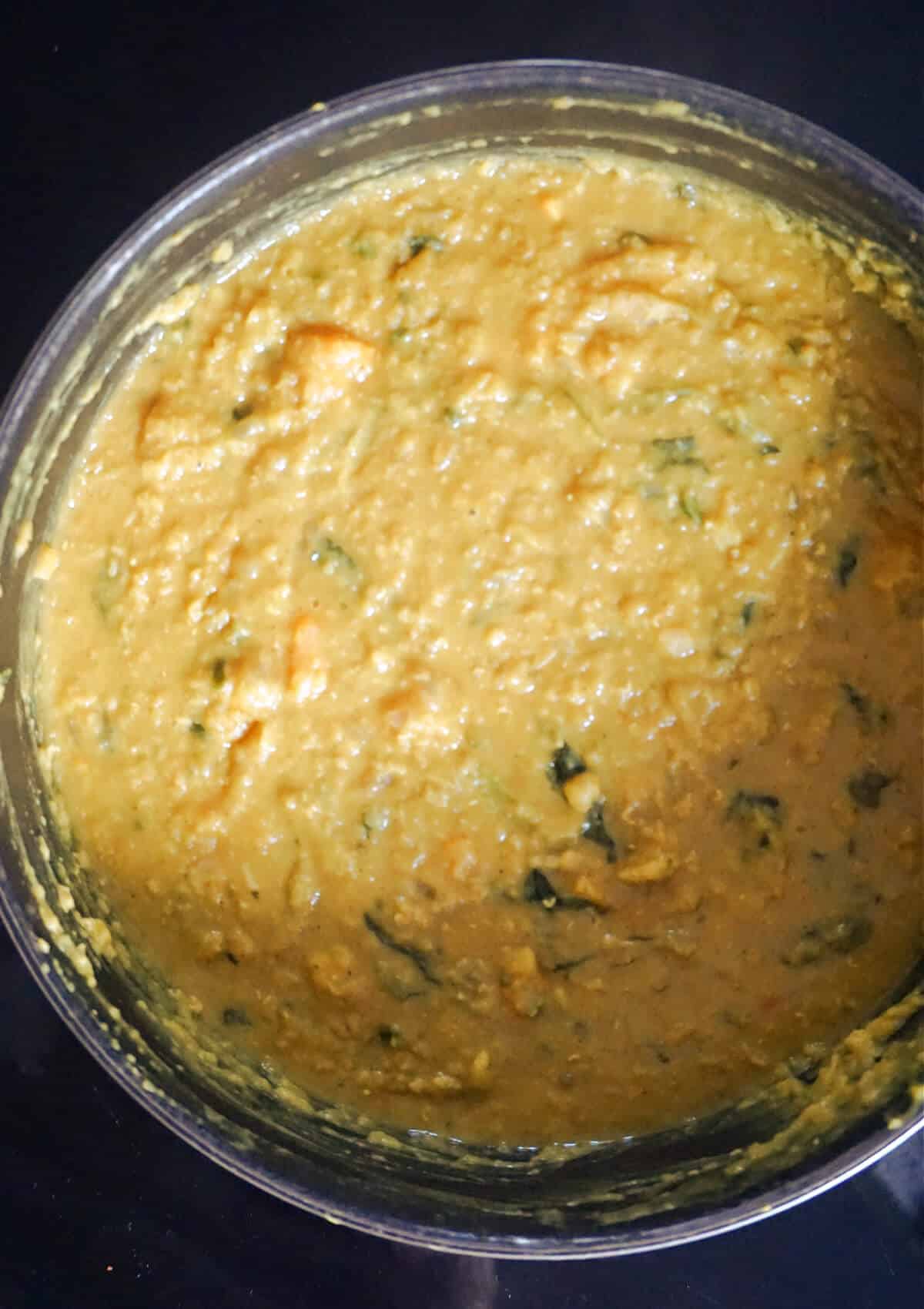 Overhead shot of a pan with red lentil, coconut milk , spinach and sweet potato dahl.