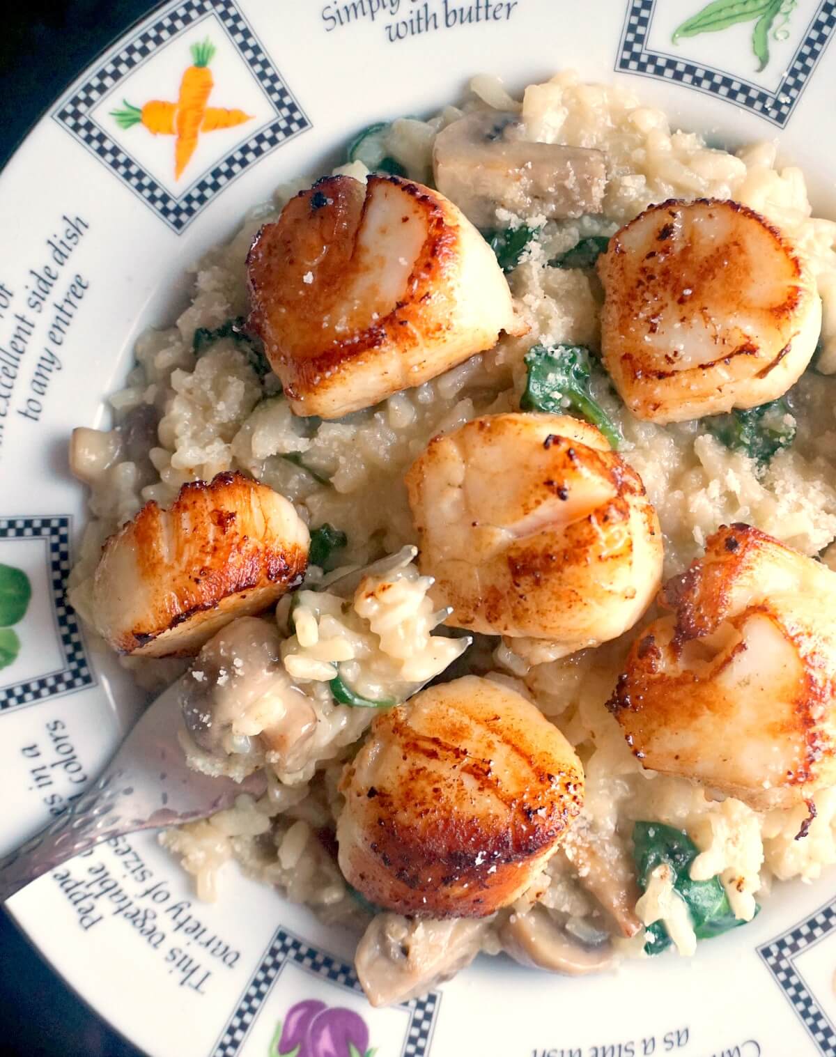 A plate with risotto topped with seared scallops.