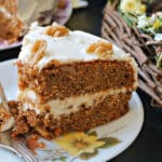A slice of carrot cake on a white flowery plate.