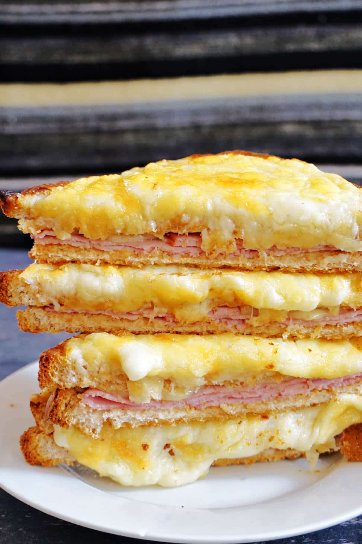 A stack of croque monsieur on a white plate.