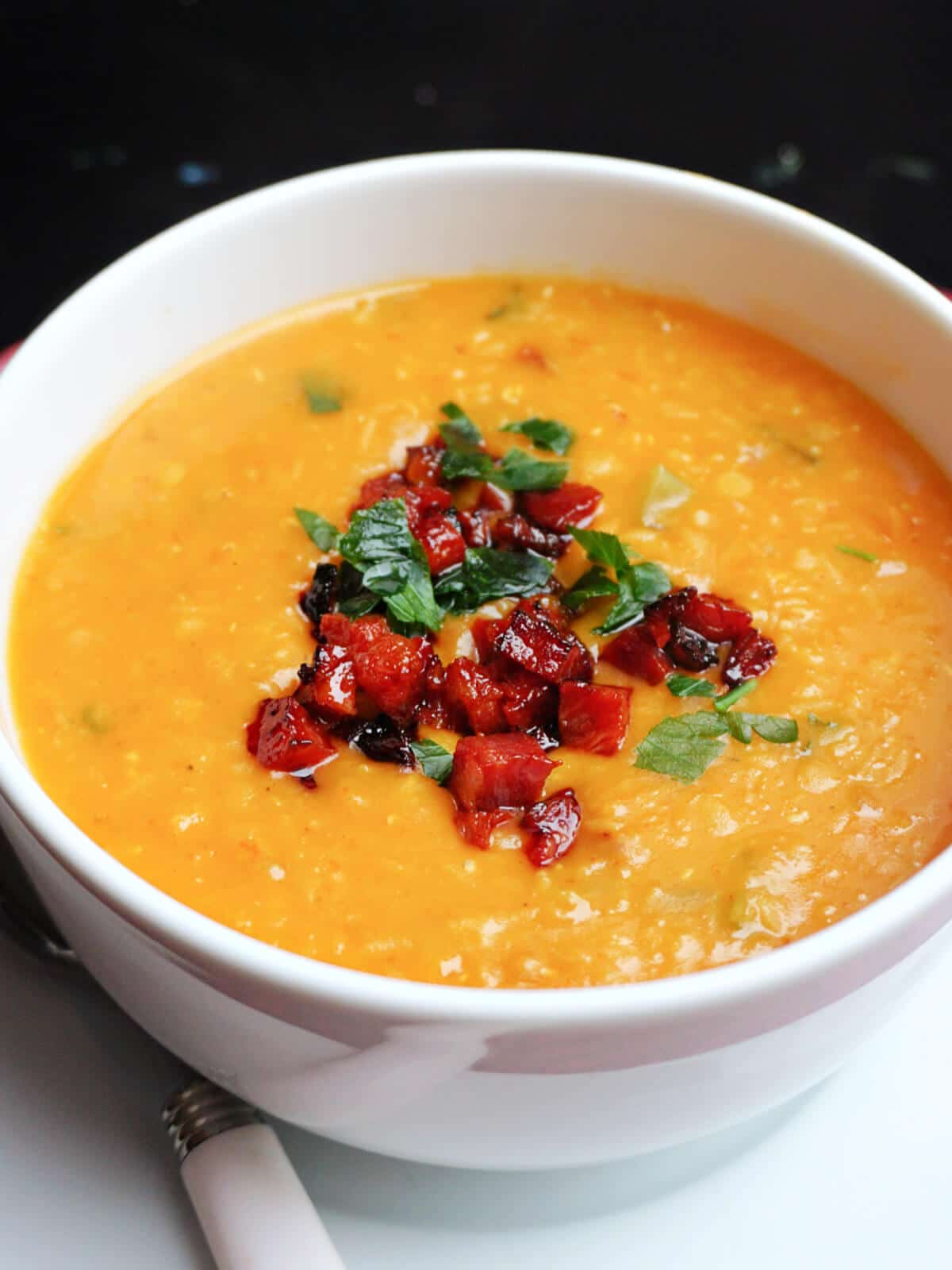 A white bowl with lentil and chorizo soup.