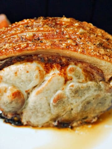 A piece of roast pork with crackling on a plate.