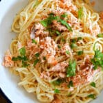 A white bowl with spaghetti carbonara with salmon.