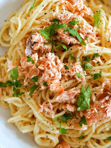 A white bowl with spaghetti carbonara with salmon.