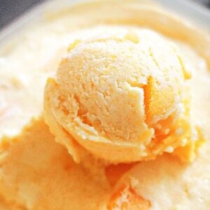 Close-up shot of a scoop of peach ice cream in an ice cream container