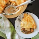 A white plate with a serving of chicken pie and a dish with more pie