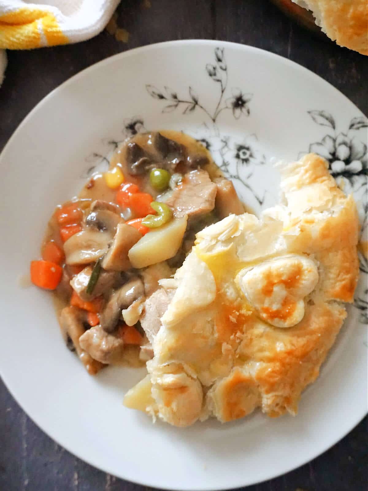 A white plate with leftover roast beef with veggies and puff pastry.