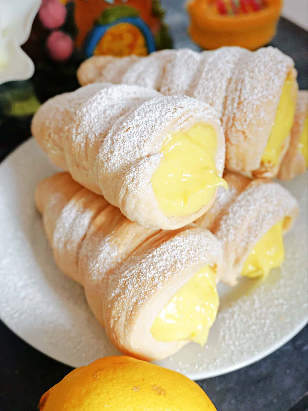 A pile of 5 lemon cream horns on a white plate.