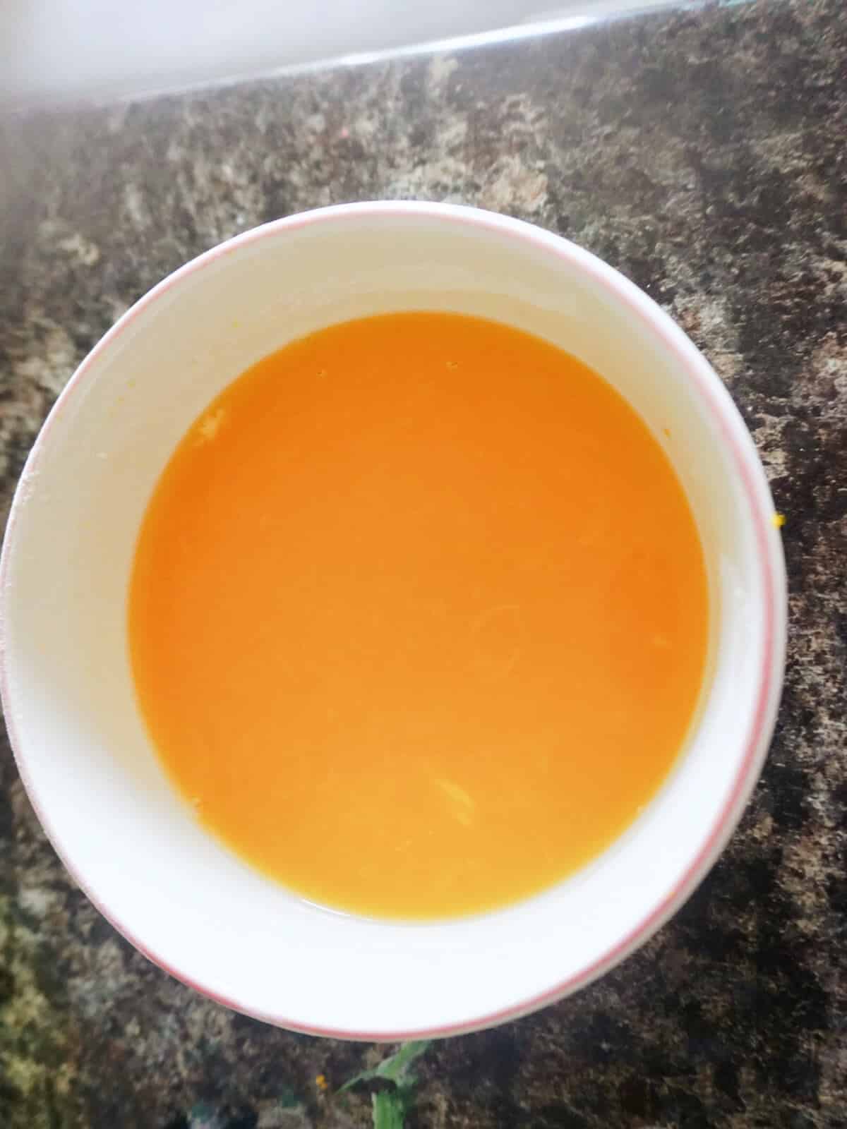 A white ramekin with orange drizzle