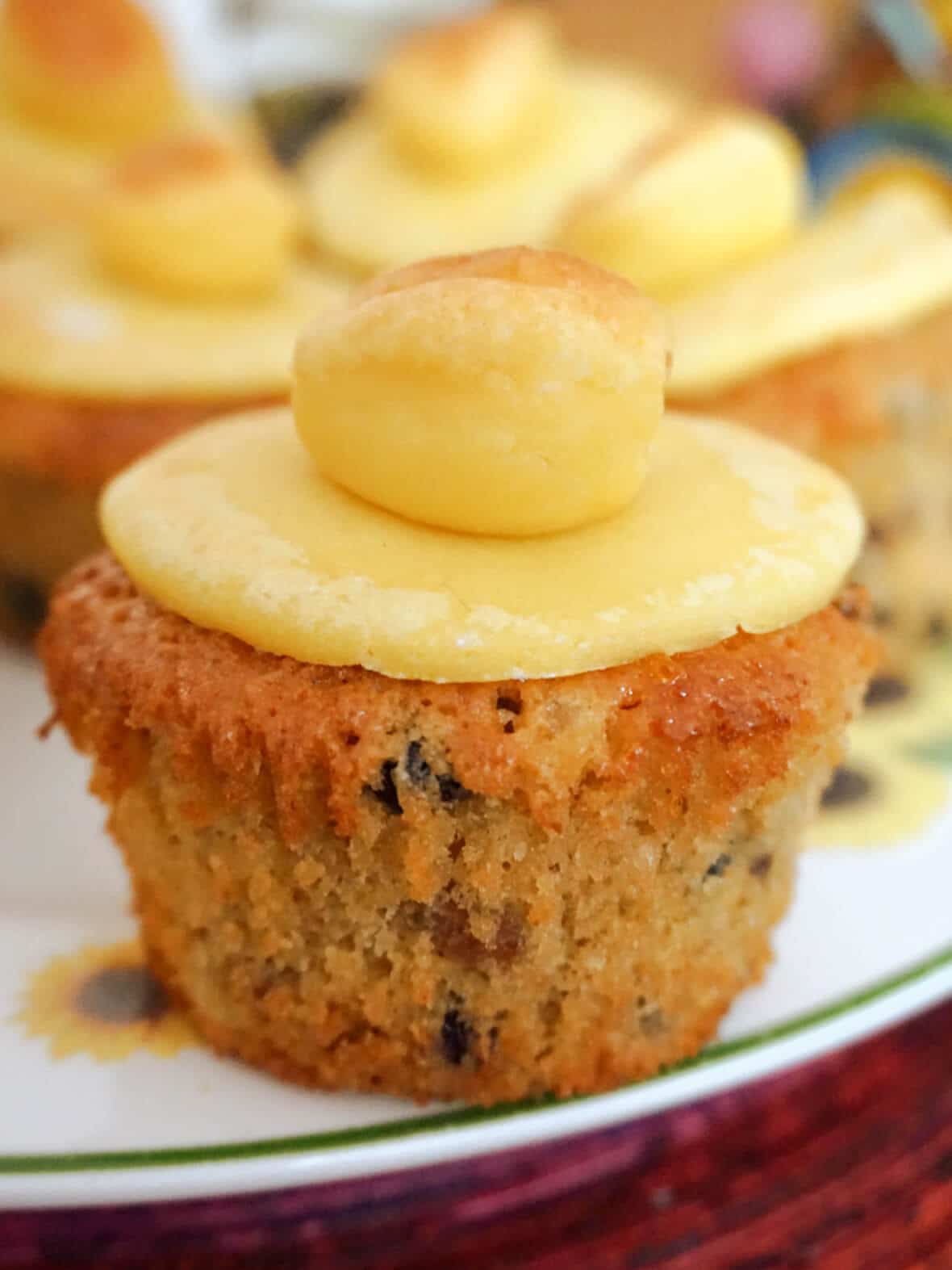 A simnel cupcake on a white plate with more cupcakes in the background