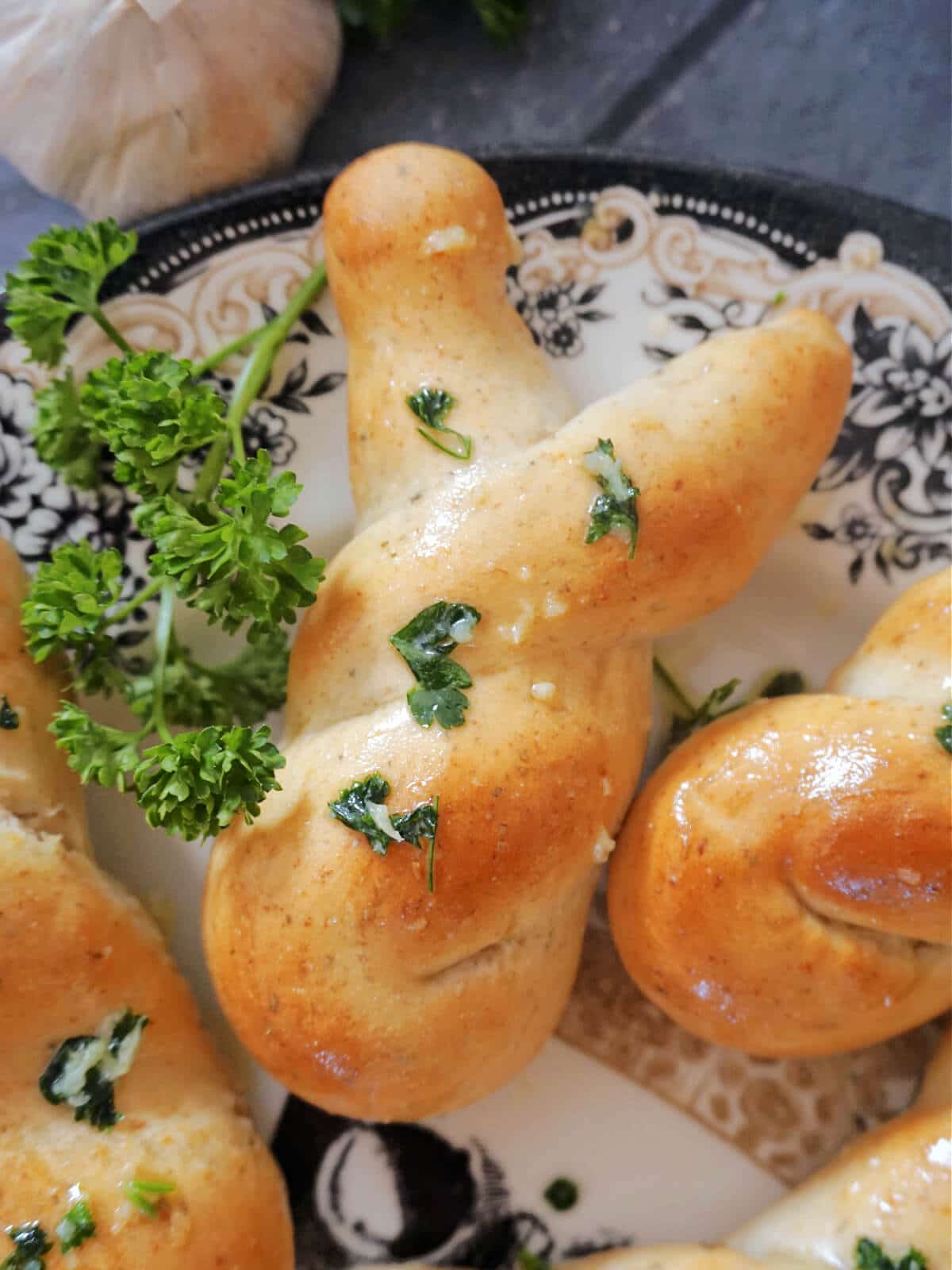 Overhead shot of a bunny-shaped garlic knot on a plate with fresh parsley