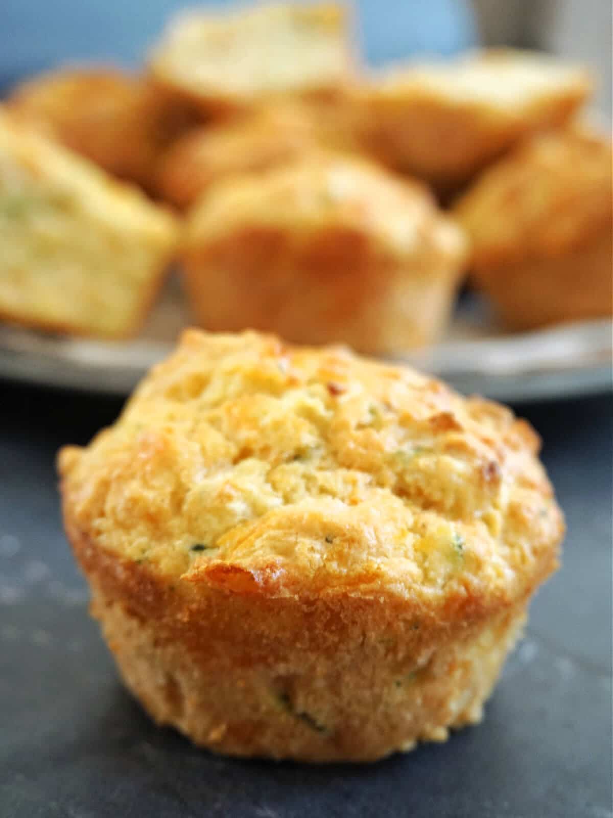 Close-up shot of a carrot and courgette muffins with more muffins in the background.