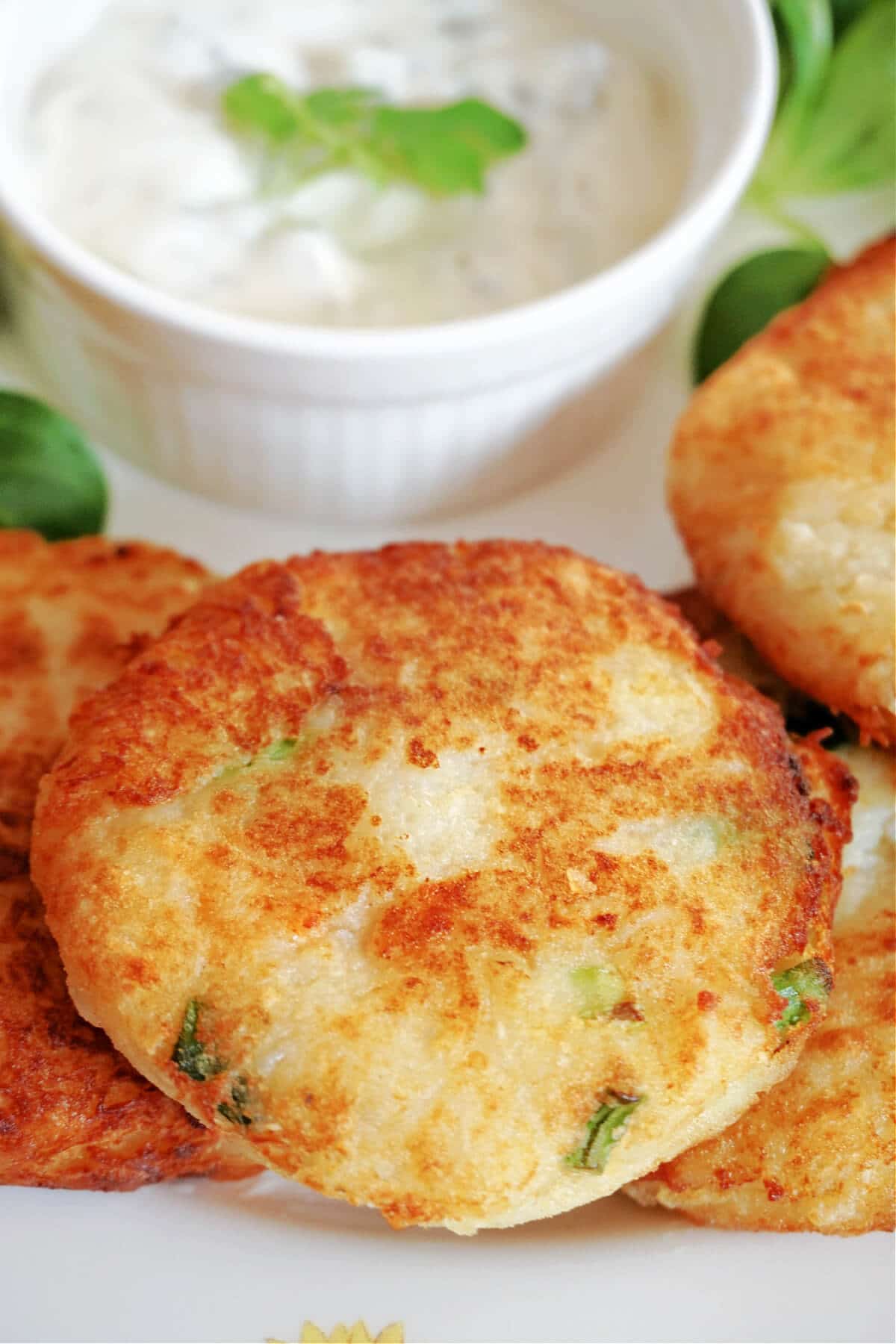 Close-up shot of crab cakes with a ramekin of tartar sauce.