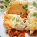 Close-up shot of enchiladas on a white flowery plate