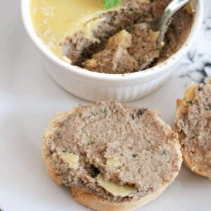 A slice of baguette spread with pate and a white ramekin with more pate next to it