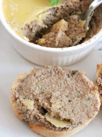 A slice of baguette spread with pate and a white ramekin with more pate next to it