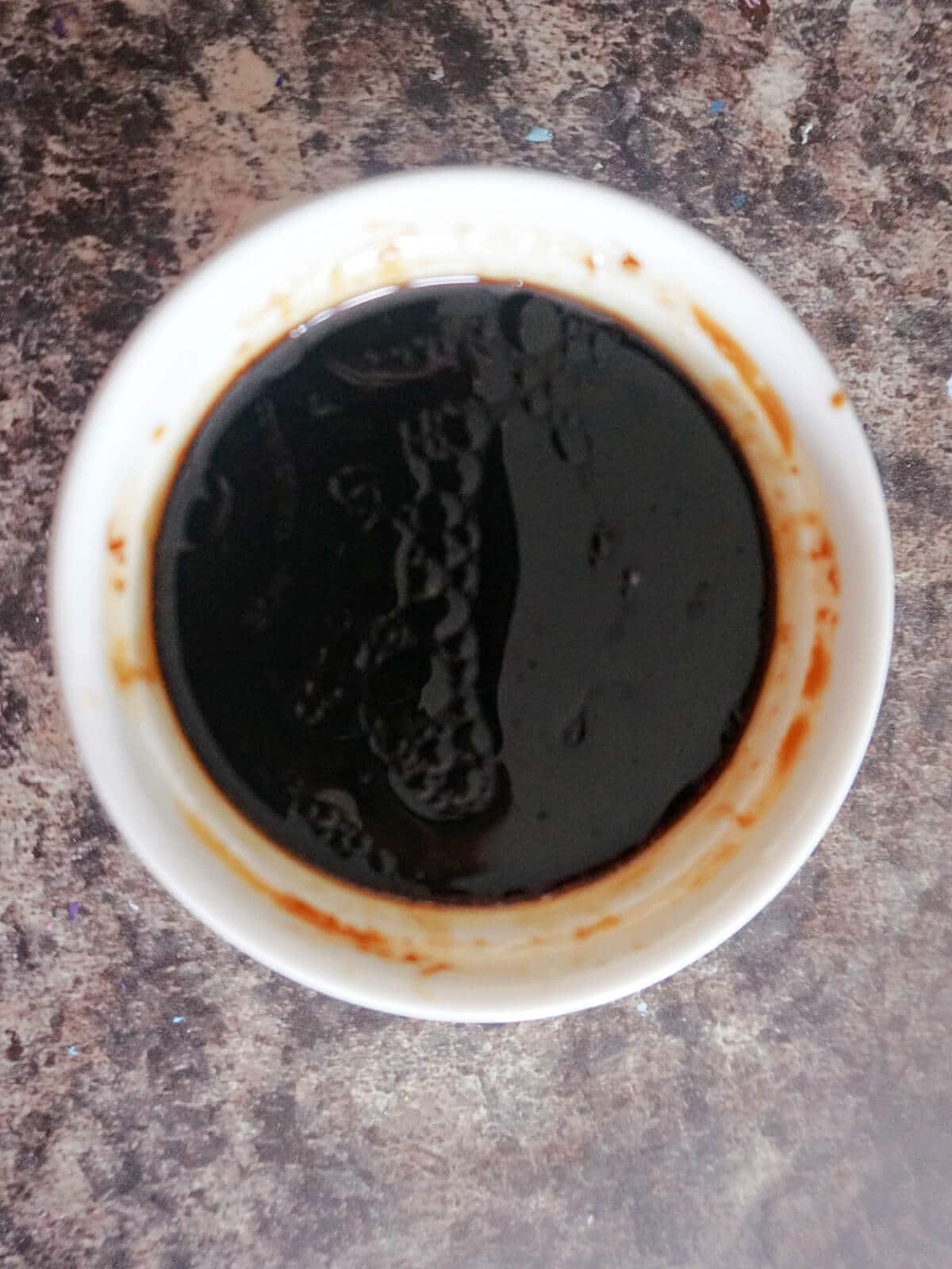 Overhead shot of a white ramekin with stir fry sauce.