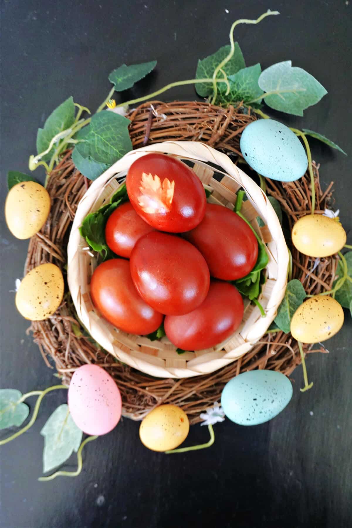 Overhead shoot of a basket of red eggs around an Easter wreath.