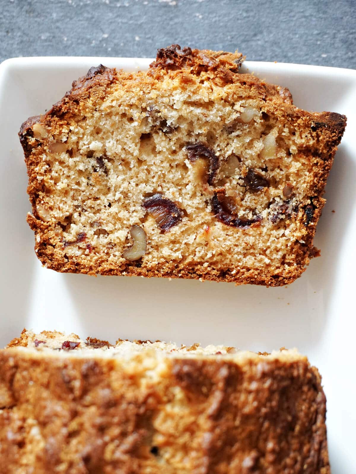 A slice of walnut and date cake on a white plate