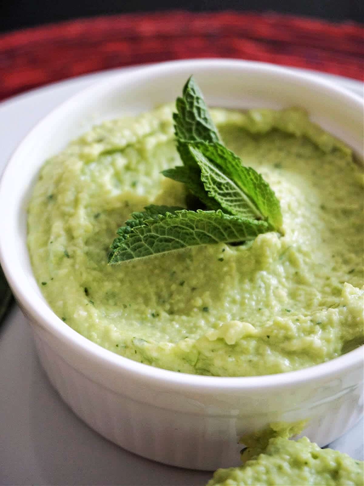 Close- up shot of a white ramekin with broad bean hummus.