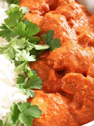 Close-up shot of butter chicken, rice and parsley