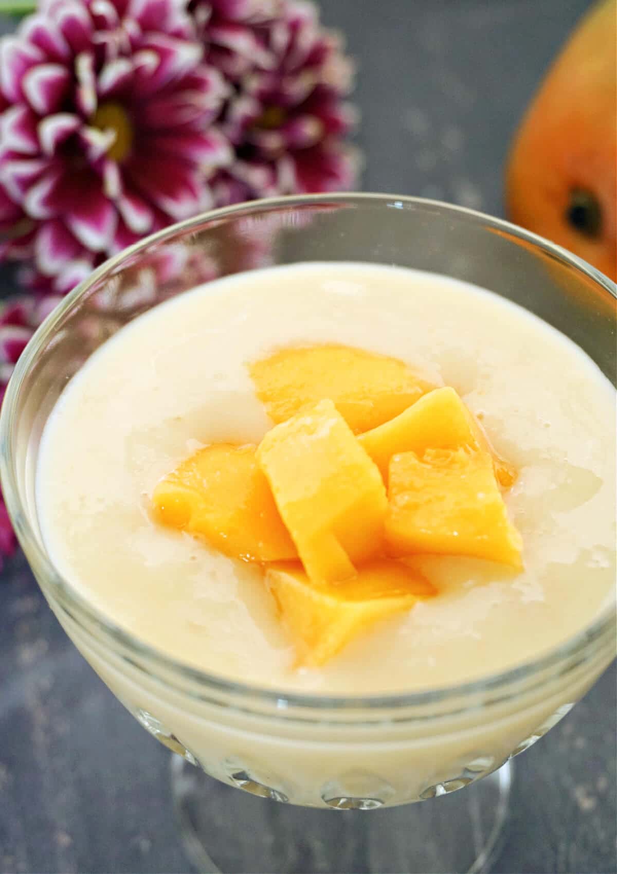 A dessert glass with custard and mango chunks.