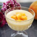 A dessert glass with custard and mango chunks