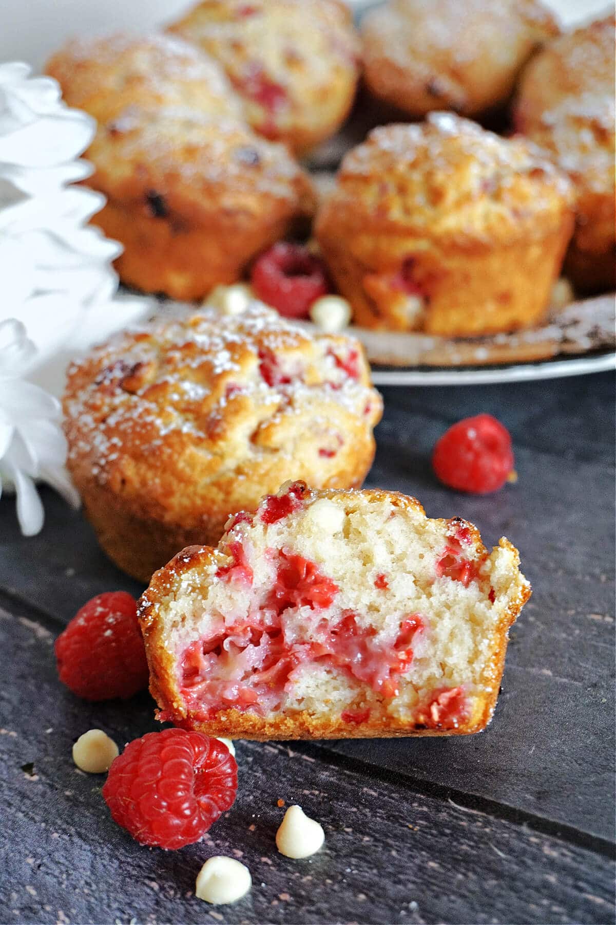 Half of a raspberry muffin with more muffins in the background