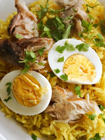 A white plate with rice, sliced boiled eggs and smoked mackerel flakes.