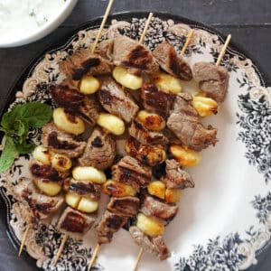 A plate with 4 skewers with gnocchi and beef cubes