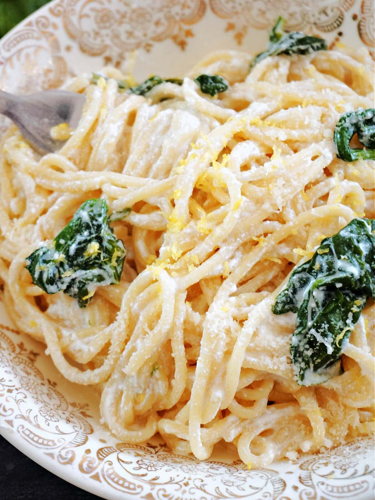 Close- up shot of a plate with spaghetti with spinach, ricotta and lemon.