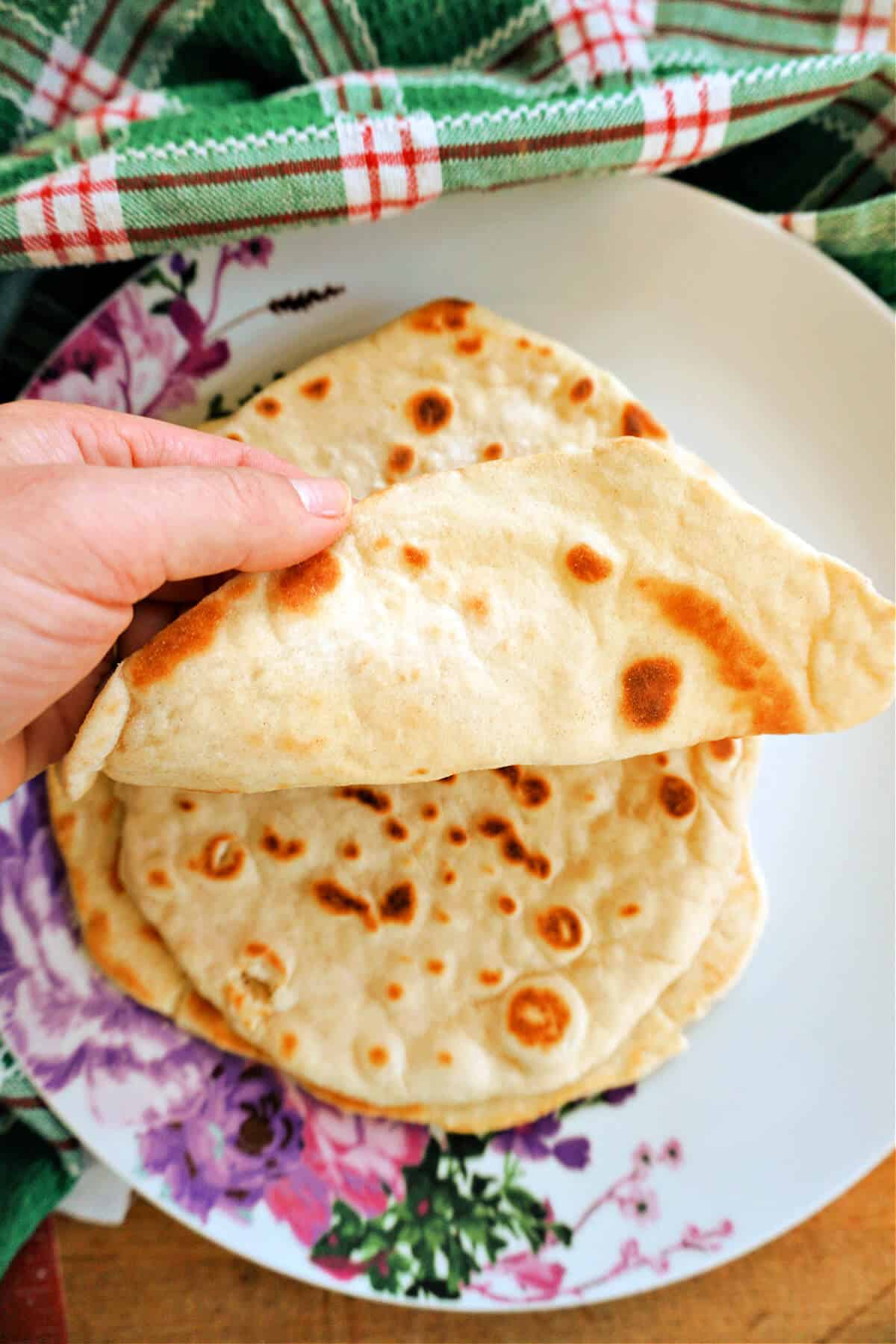 A hand showing a pile of flatbreads.