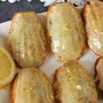 6 lemon madeleines covered in white chocolate and topped with lemon zest