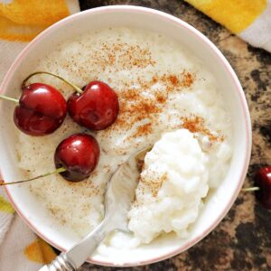 Overhead shot of a white bowl of rice with 3 cherries on top