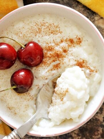 Overhead shot of a white bowl of rice with 3 cherries on top