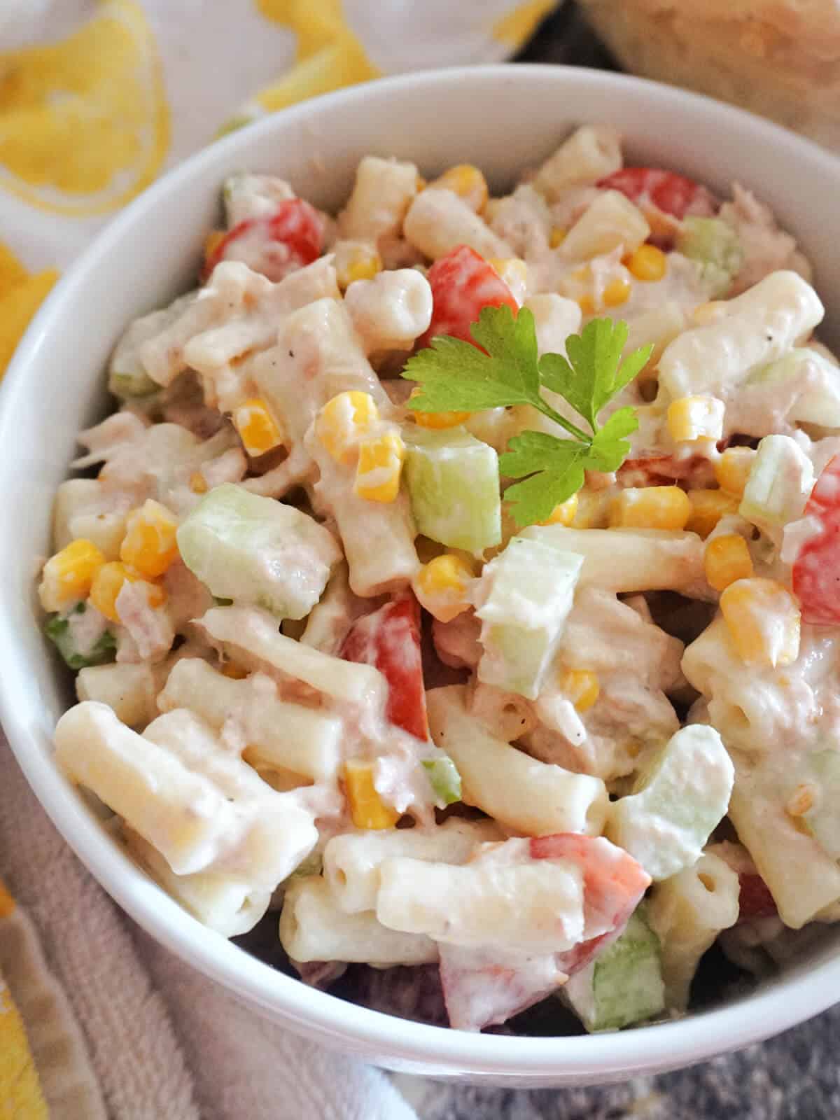 Close-up shot of a white bowl with pasta with tuna and veggies