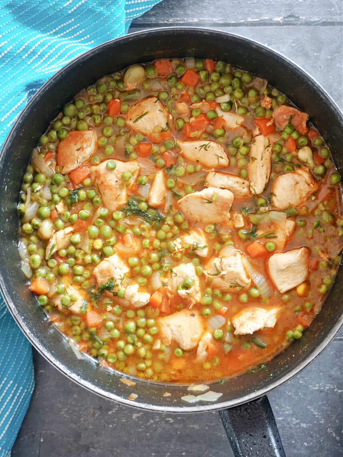 Overhead shot of a pan with chicken pieces and pea stew.