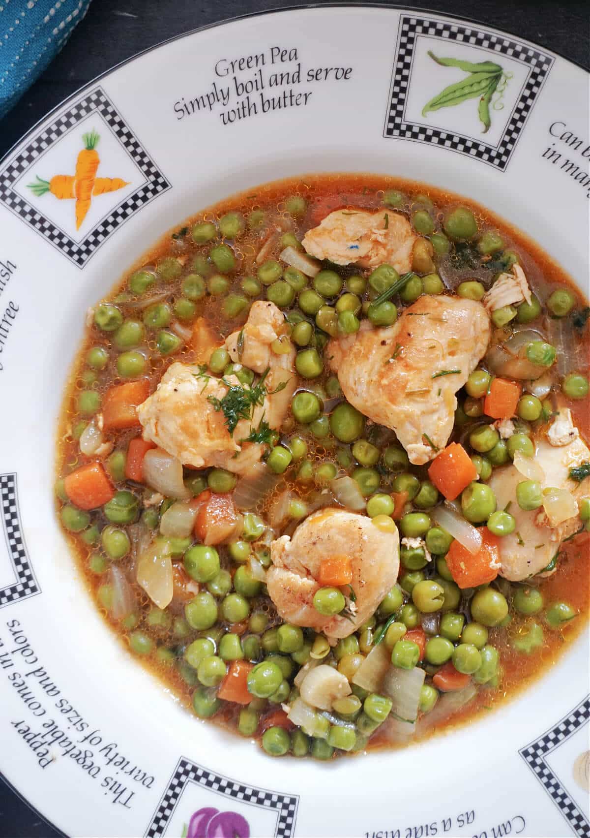 Close-up shot of a white plate with chicken and pea stew