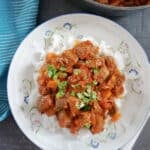 Overhead shot of a white plate with rice and chilli garnished with parsley