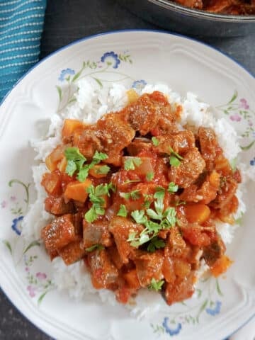 Overhead shot of a white plate with rice and chilli garnished with parsley