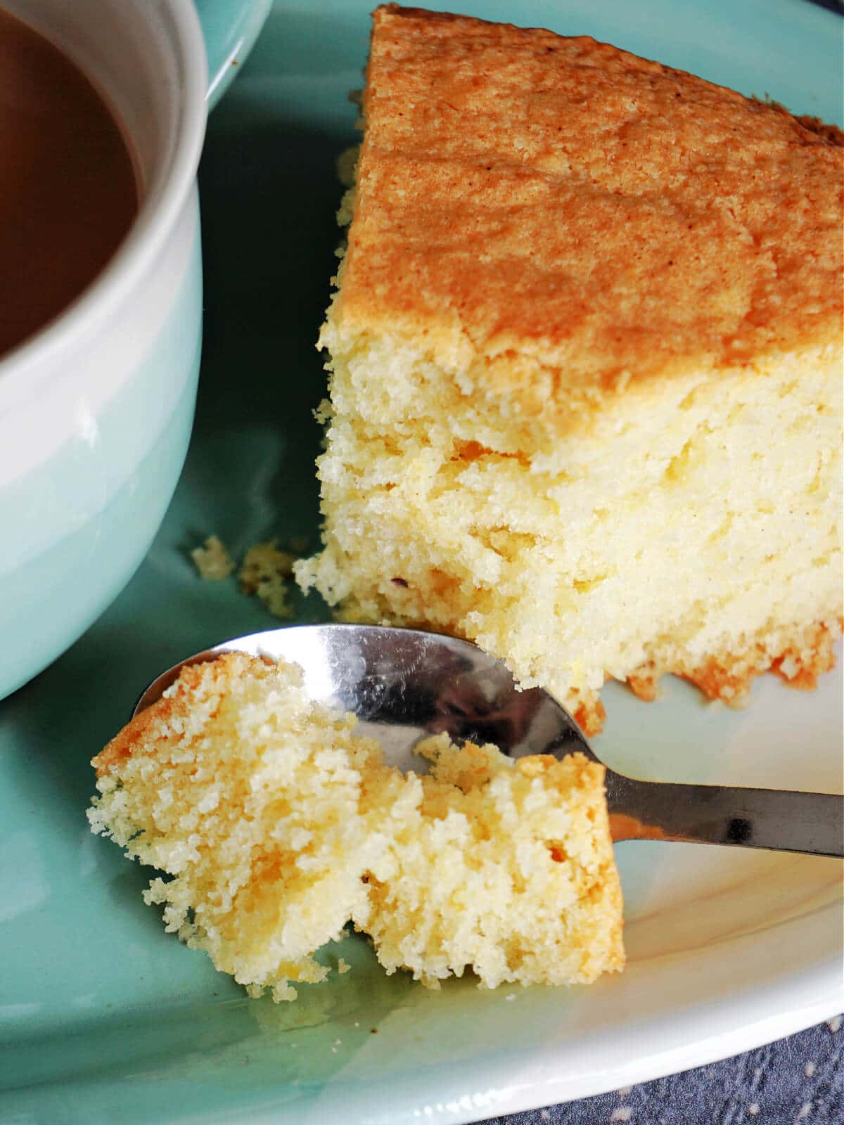 Close-up shot of a dessert spoon cutting into a slice of madeira cake