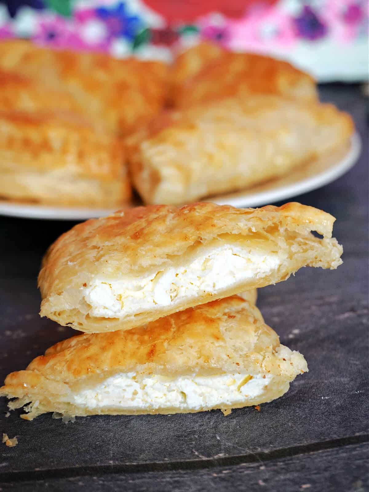 2 halves of a cheese pastry with more pastries in the background.