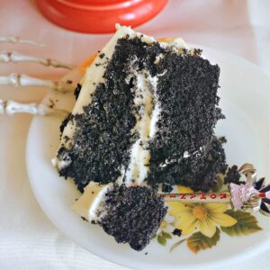 A slice of black velvet cake with frosting on a white plate