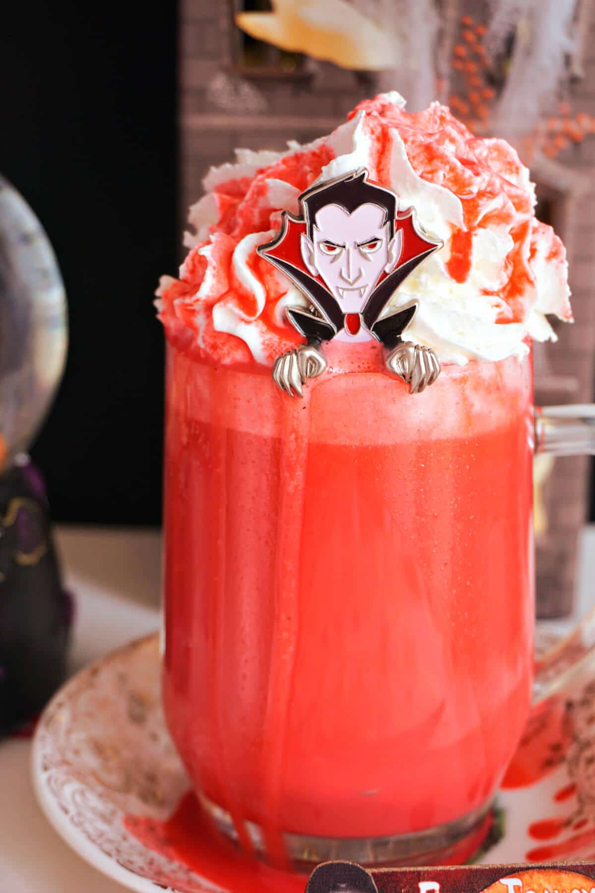 A glass of red hot chocolate with a dracula spoon in it.